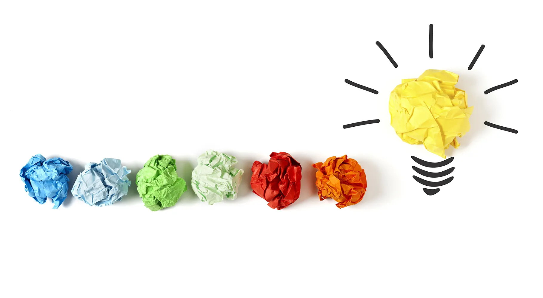 Crumpled pieces of paper leading to a lightbulb
